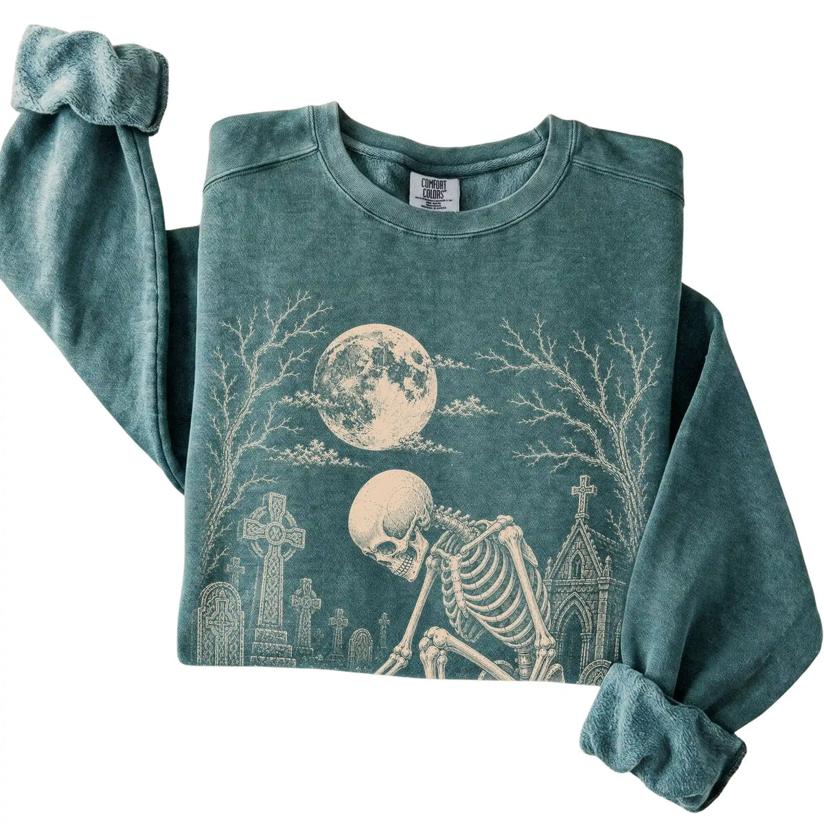 Folded Blue Spruce sweatshirt with a skeleton petting a Chihuahua in a graveyard