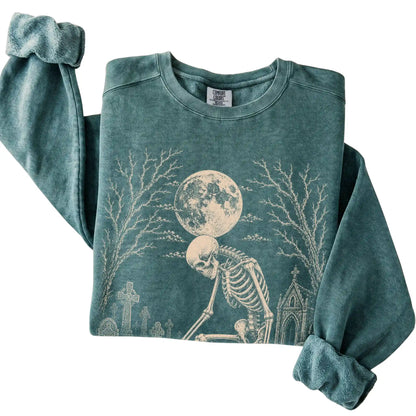 Folded Blue Spruce sweatshirt with a skeleton petting a Corgi in a graveyard