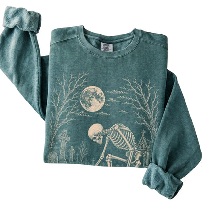 Folded Blue Spruce sweatshirt with a skeleton petting a Dachshund in a graveyard