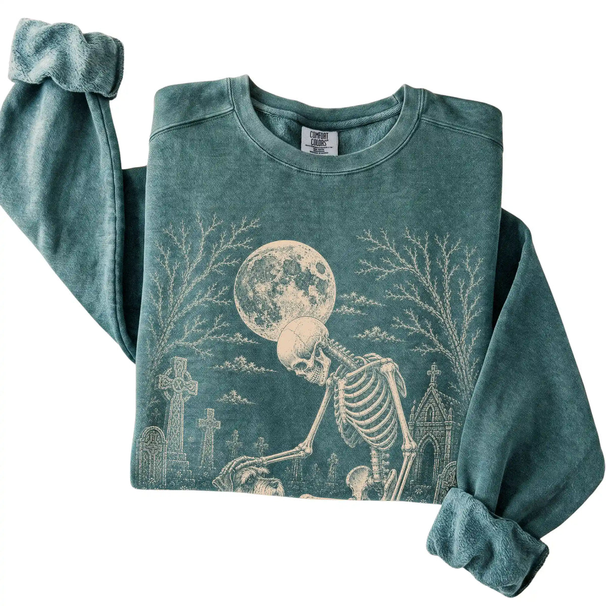 Folded Blue Spruce sweatshirt with a skeleton petting a Schnauzer in a graveyard