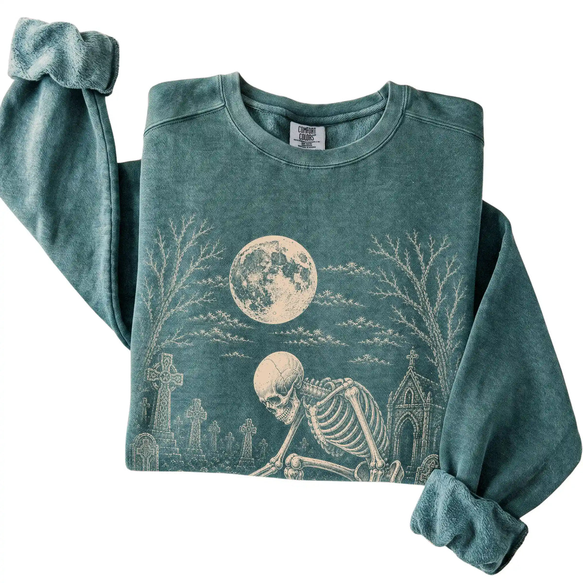 Folded Blue Spruce sweatshirt with a skeleton petting a Yorkie in a graveyard