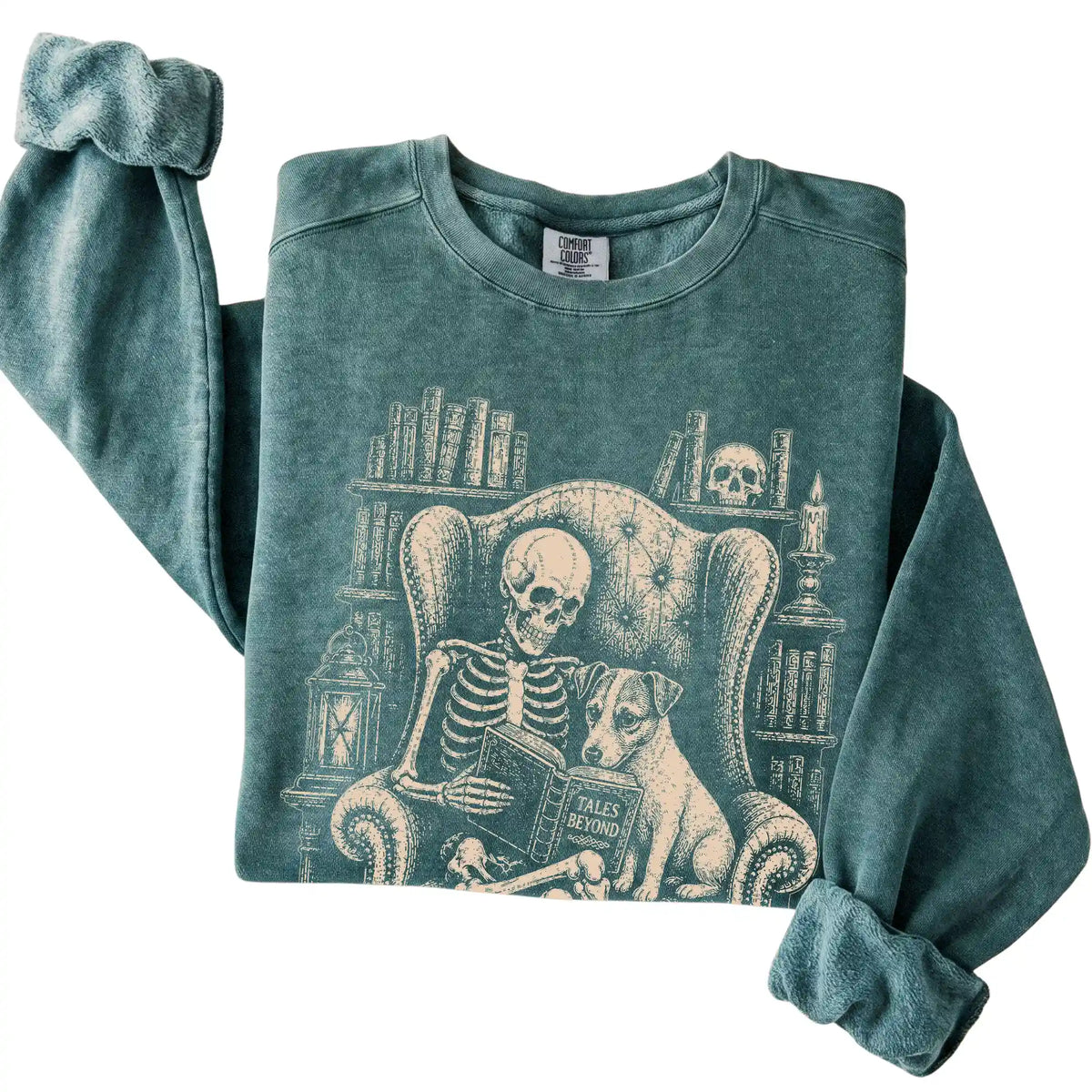 Folded Blue Spruce sweatshirt with a skeleton reading Tales Beyond to a Jack Russell