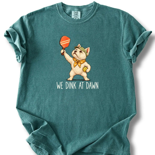 Westie with a pickleball paddle and ball on a Blue Spruce Comfort Colors® T-shirt with We Dink at Dawn text