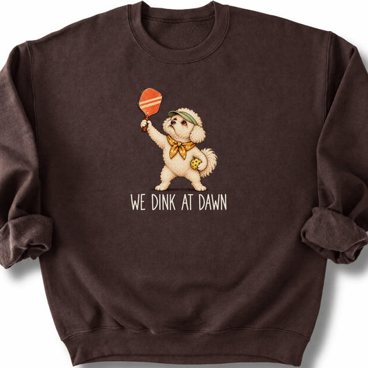 Bichon Frise with a pickleball paddle and ball on a Dark Chocolate Gildan® sweatshirt with We Dink at Dawn text