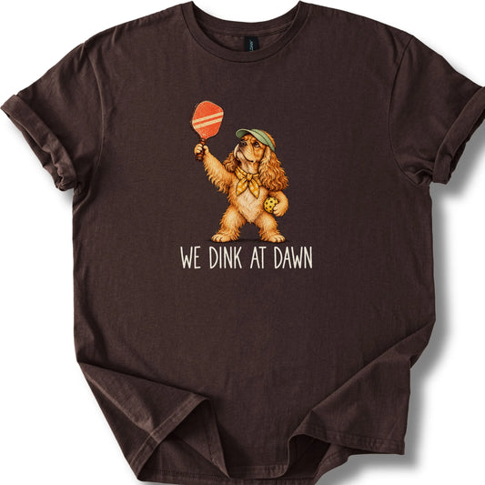 Cocker Spaniel with a pickleball paddle and ball on a Dark Chocolate Gildan® T-shirt with We Dink at Dawn text