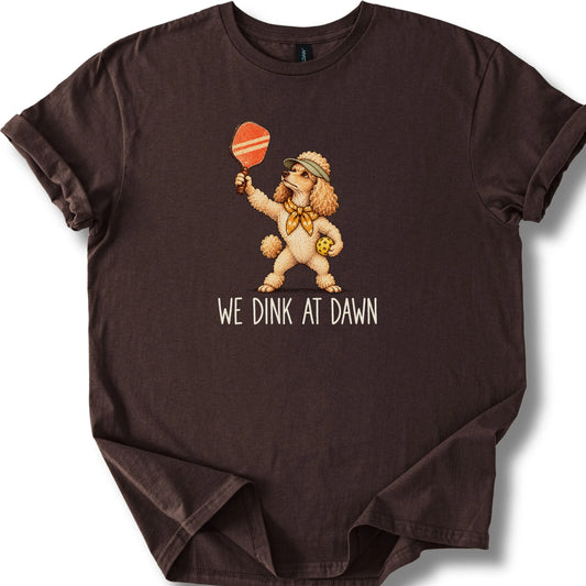 Poodle with a pickleball paddle and ball on a Dark Chocolate Gildan® T-shirt with We Dink at Dawn text