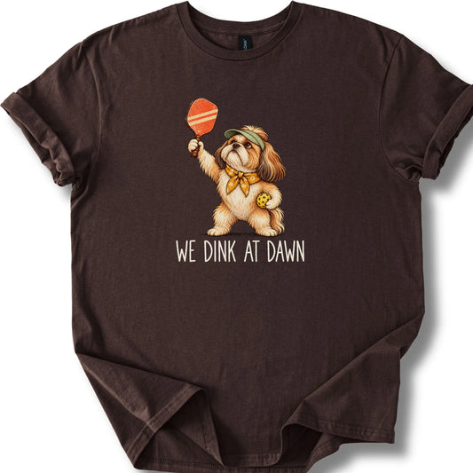 Shih Tzu with a pickleball paddle and ball on a Dark Chocolate Gildan® T-shirt with We Dink at Dawn text