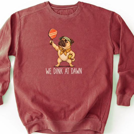 Pug with a pickleball paddle and ball on a Crimson Comfort Colors® sweatshirt with We Dink at Dawn text