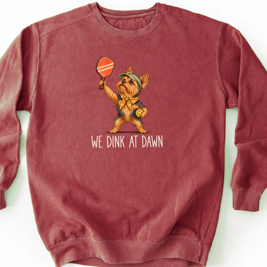 Yorkie with a pickleball paddle and ball on a Crimson Comfort Colors® sweatshirt with We Dink at Dawn text