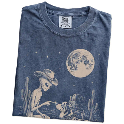 Folded Denim Comfort Colors® T-shirt showing cowboy alien fist-bumping a australian shepherd beneath the moon