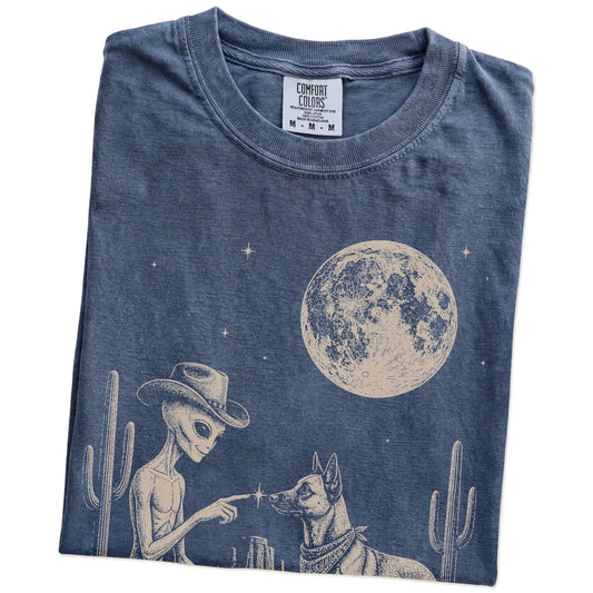Folded Denim Comfort Colors® T-shirt showing cowboy alien fist-bumping a belgian malinois beneath the moon