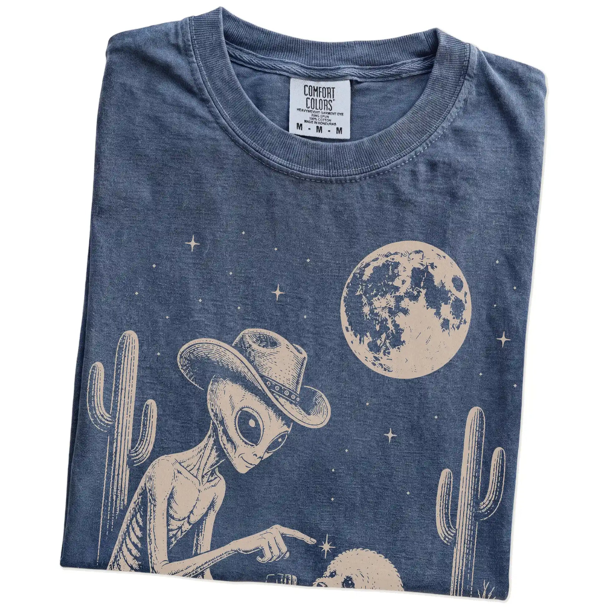 Folded Denim Comfort Colors® T-shirt showing cowboy alien fist-bumping a bichon frise beneath the moon