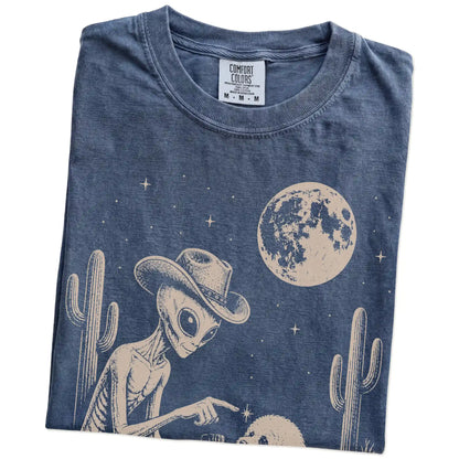Folded Denim Comfort Colors® T-shirt showing cowboy alien fist-bumping a bichon frise beneath the moon