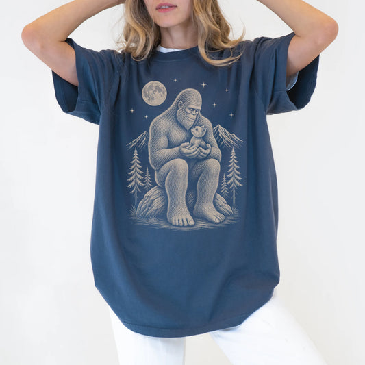 Model wearing a Denim Comfort Colors® T-shirt showing Bigfoot holding a Yorkie
