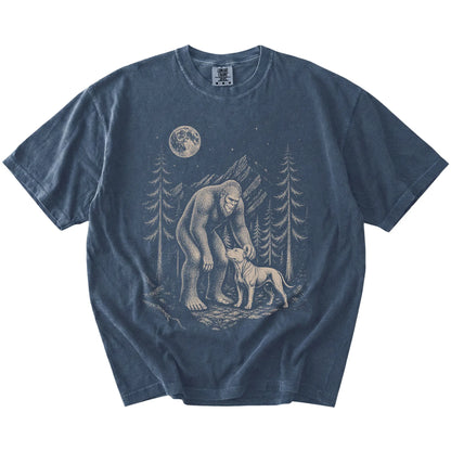 Bigfoot petting a Pitbull beneath the moon in a pine forest on a Denim Comfort Colors® T-shirt