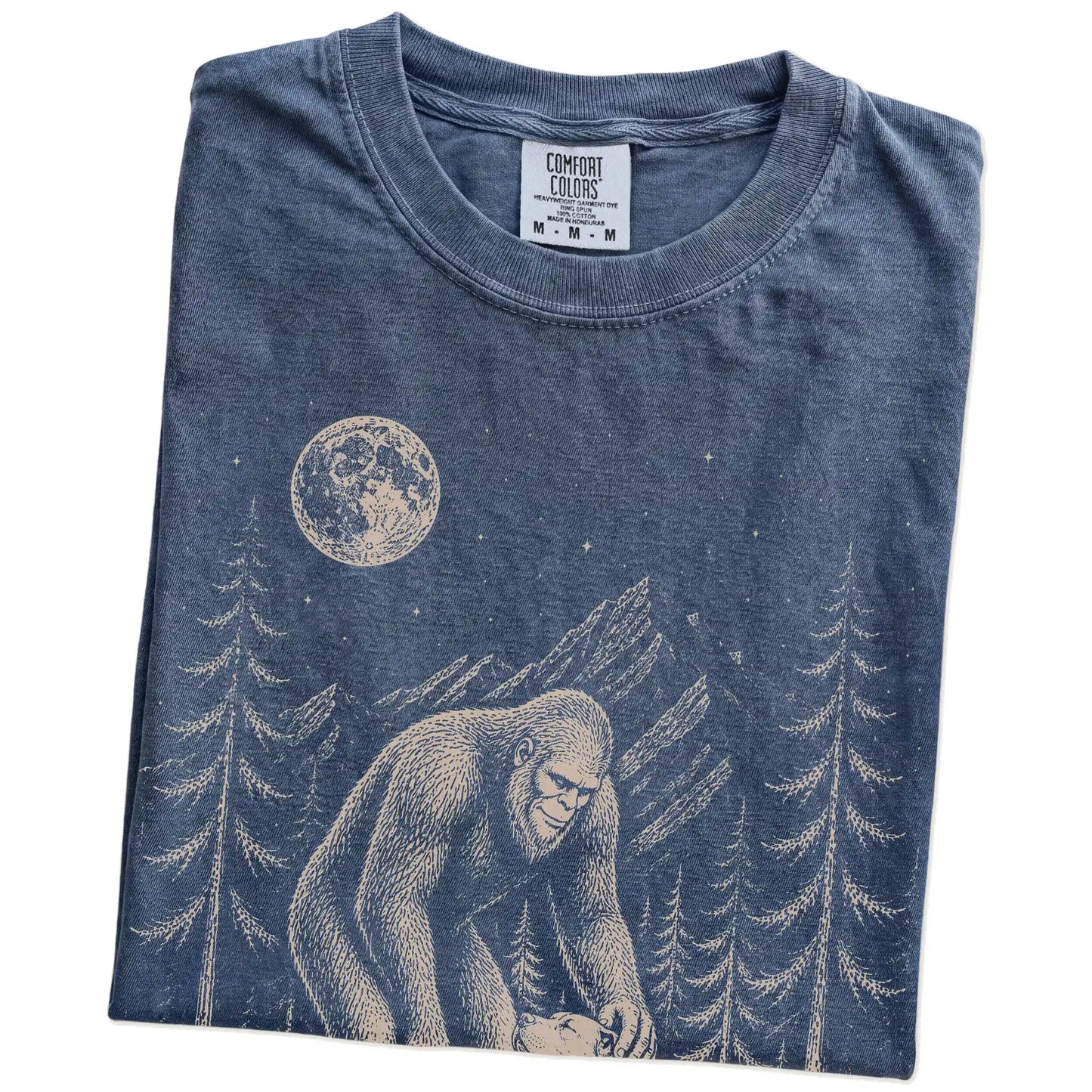 Folded Denim Comfort Colors® T-shirt showing bigfoot petting a pitbull beneath the moon in a pine forest