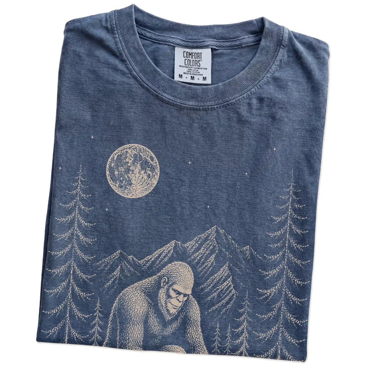 Folded Denim Comfort Colors® T-shirt showing bigfoot petting a yorkie beneath the moon in a pine forest