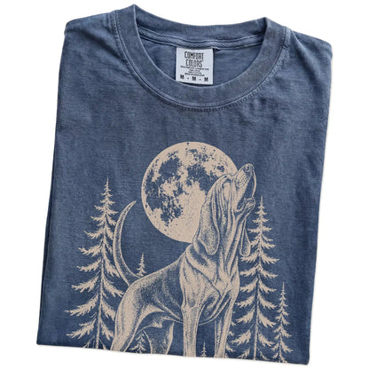 Folded Denim Comfort Colors® T-shirt showing a Bloodhound howling beneath the moon and pine trees