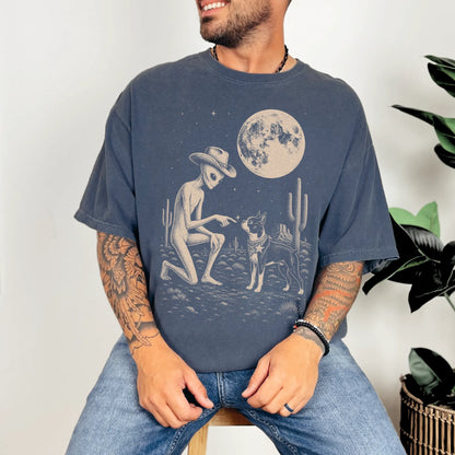 Model wearing a Denim Comfort Colors® T-shirt with cowboy alien fist-bumping a boston terrier beneath the moon