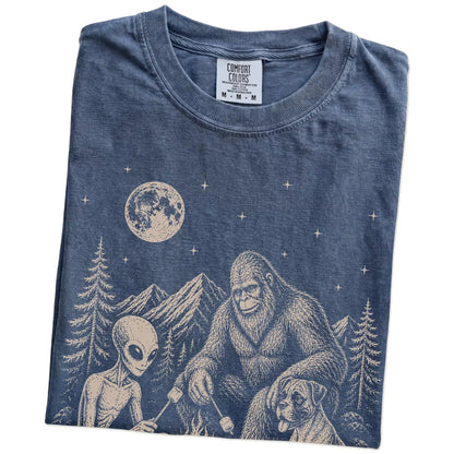 Folded Denim Comfort Colors® T-shirt showing Boxer camping with Bigfoot and an alien