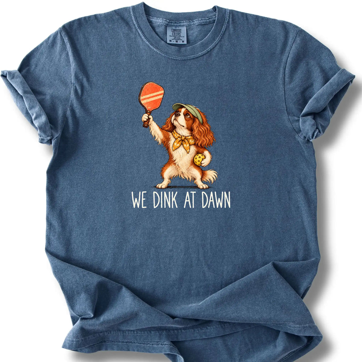 Cavalier with a pickleball paddle and ball on a Denim Comfort Colors® T-shirt with We Dink at Dawn text