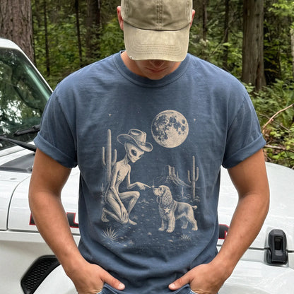 Model wearing a Denim Comfort Colors® T-shirt with cowboy alien fist-bumping a cocker spaniel beneath the moon