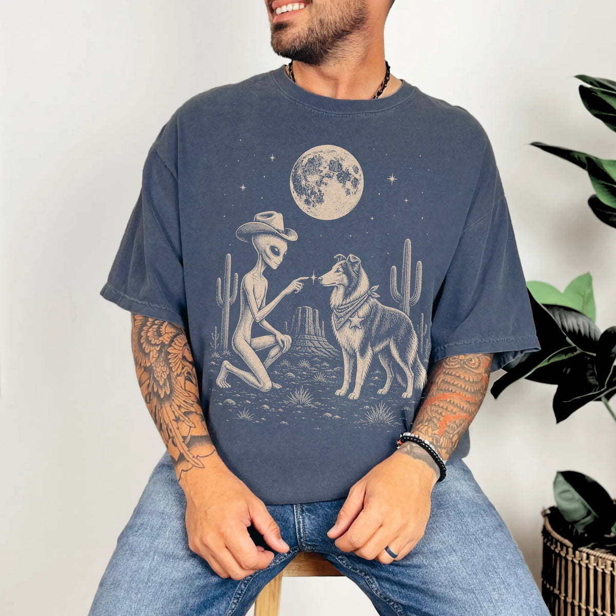Model wearing a Denim Comfort Colors® T-shirt with cowboy alien fist-bumping a collie beneath the moon