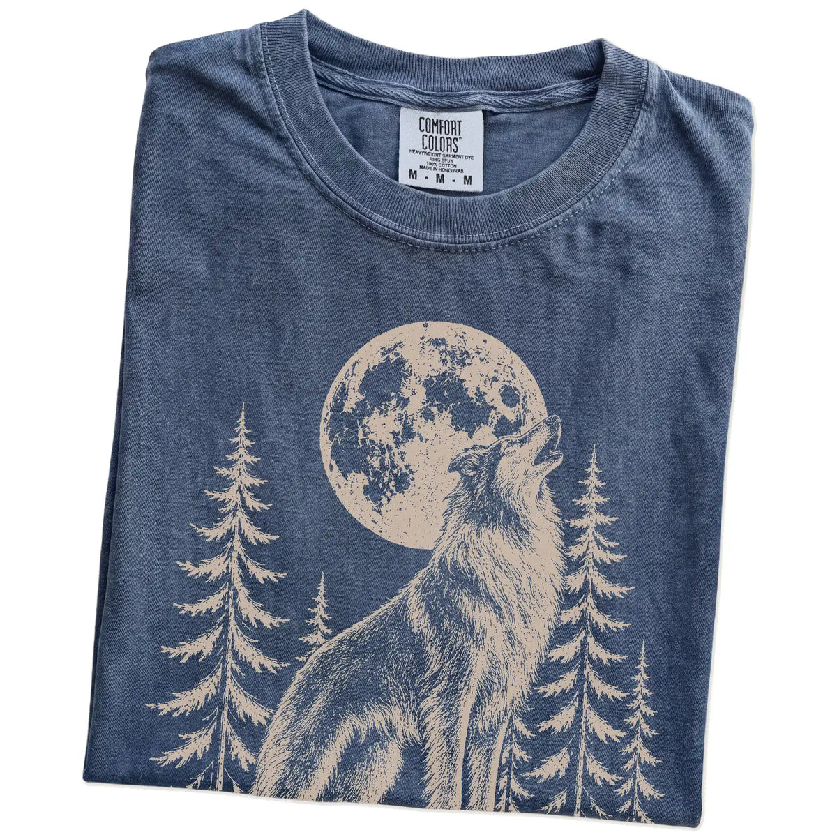 Folded Denim Comfort Colors® T-shirt showing a Collie howling beneath the moon and pine trees