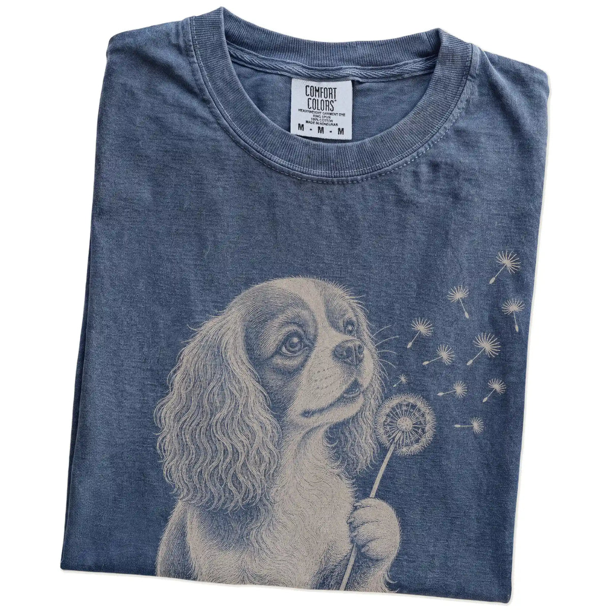 Folded Denim Comfort Colors® T-shirt showing Cavalier King Charles Spaniel portrait with drifting dandelion seeds