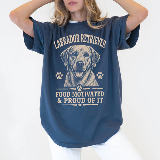 Model wearing a Denim Comfort Colors® T-shirt featuring Labrador Retriever design with “Food Motivated & Proud Of It” letteri