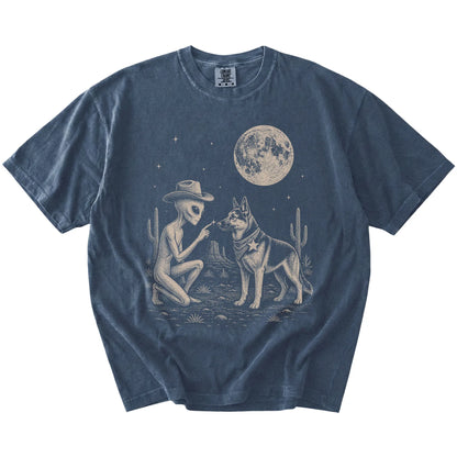 Cowboy alien fist-bumping a German Shepherd beneath the moon on a Denim Comfort Colors® T-shirt