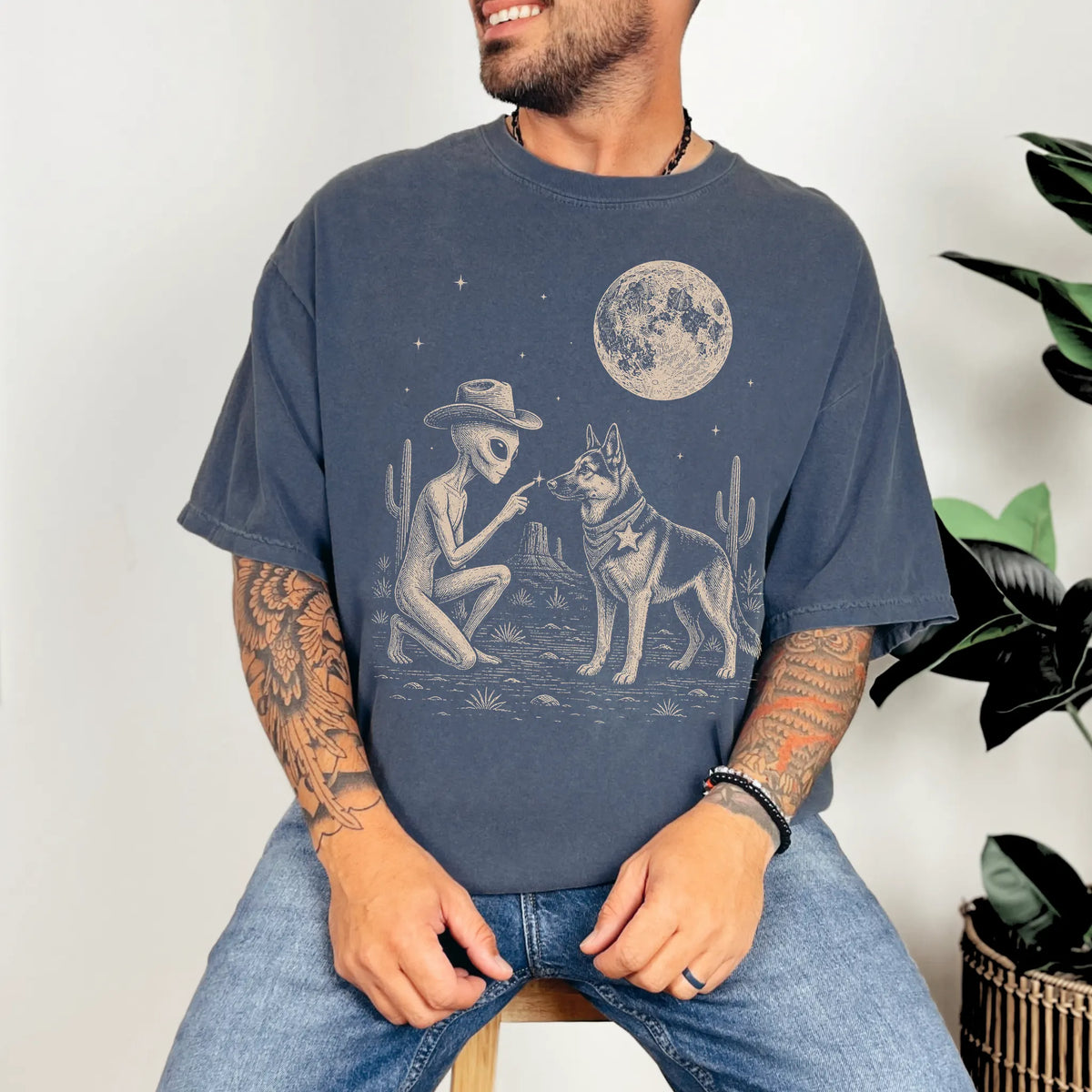 Model wearing a Denim Comfort Colors® T-shirt with cowboy alien fist-bumping a german shepherd beneath the moon