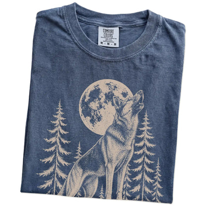 Folded Denim Comfort Colors® T-shirt showing a German Shepherd howling beneath the moon and pine trees
