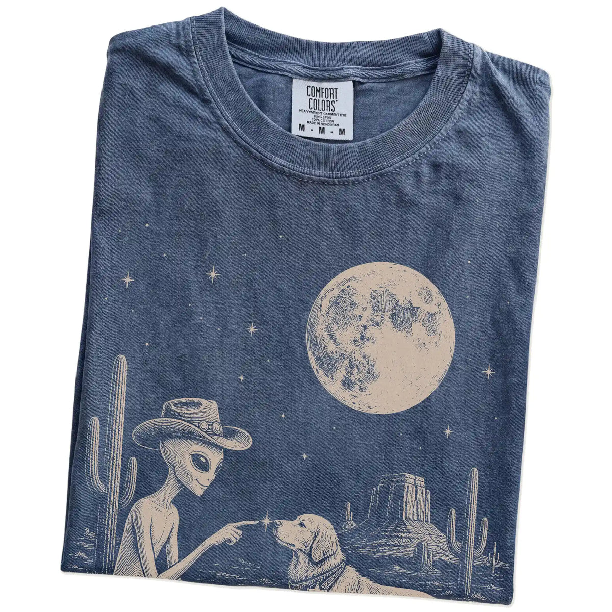 Folded Denim Comfort Colors® T-shirt showing cowboy alien fist-bumping a golden retriever beneath the moon