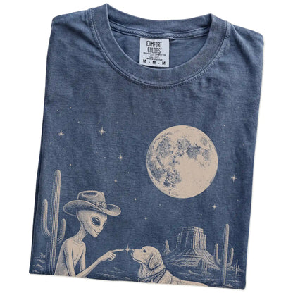 Folded Denim Comfort Colors® T-shirt showing cowboy alien fist-bumping a golden retriever beneath the moon