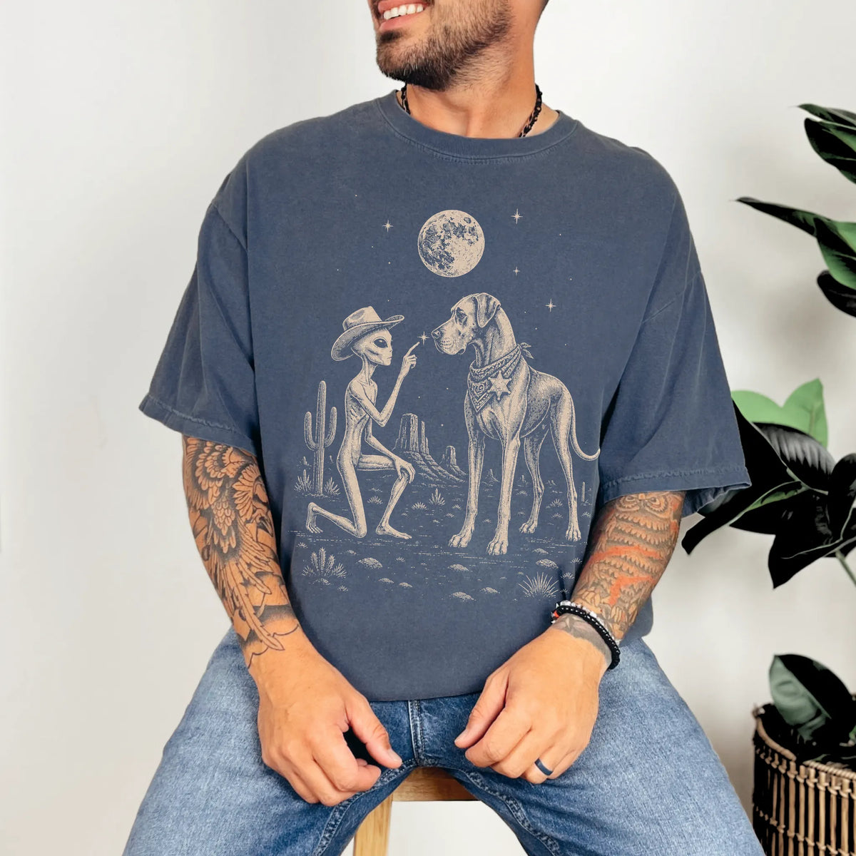 Model wearing a Denim Comfort Colors® T-shirt with cowboy alien fist-bumping a great dane beneath the moon