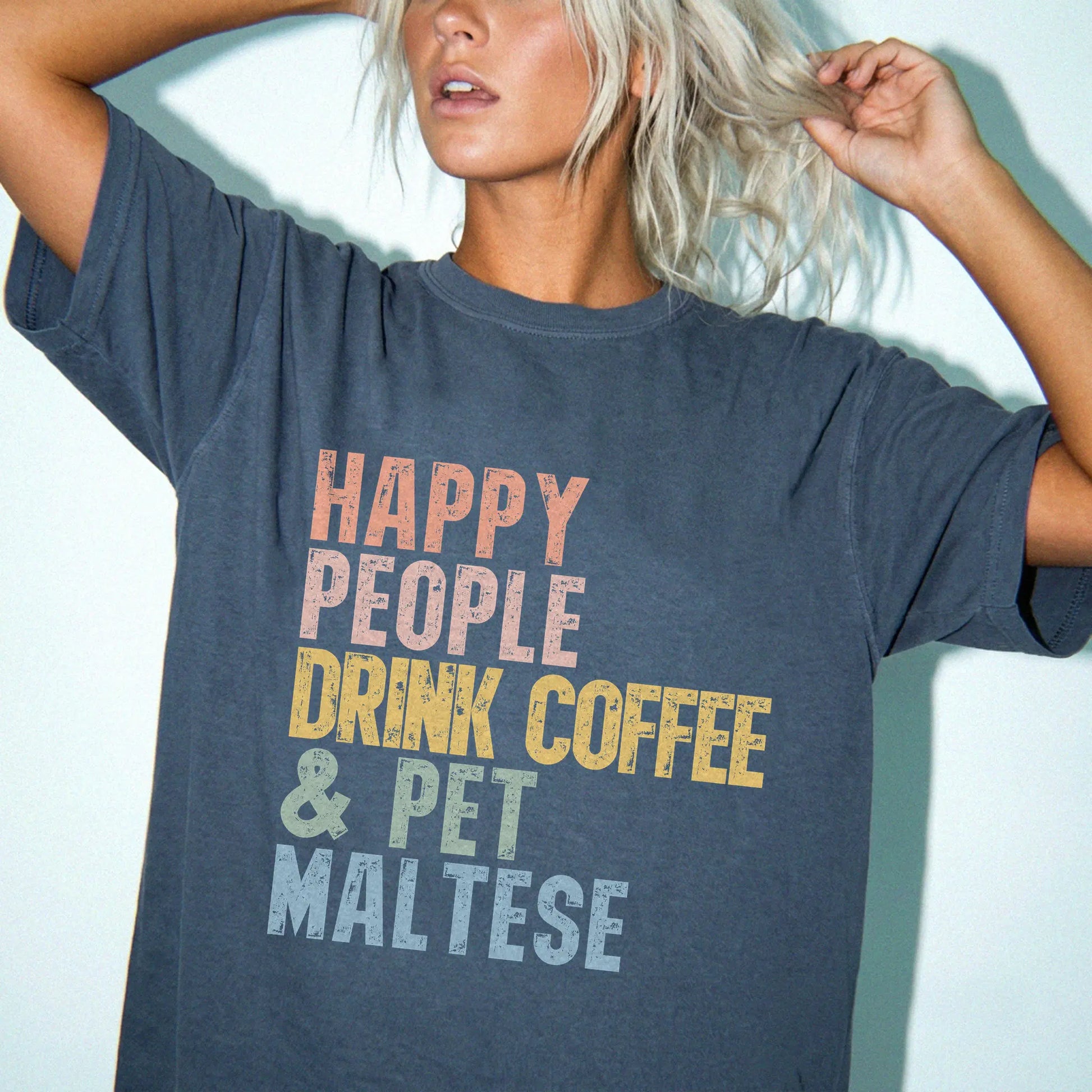 Model wearing a Denim Comfort Colors® T-shirt featuring Maltese with coffee and “Happy People Drink Coffee and Pet Dogs” lett