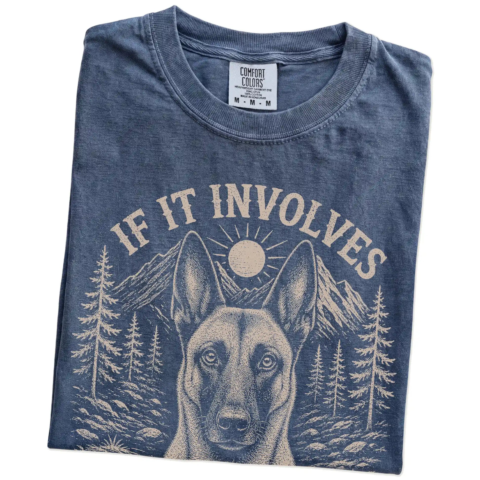 Folded Denim Comfort Colors® T-shirt showing Belgian Malinois hiking design with mountain scenery