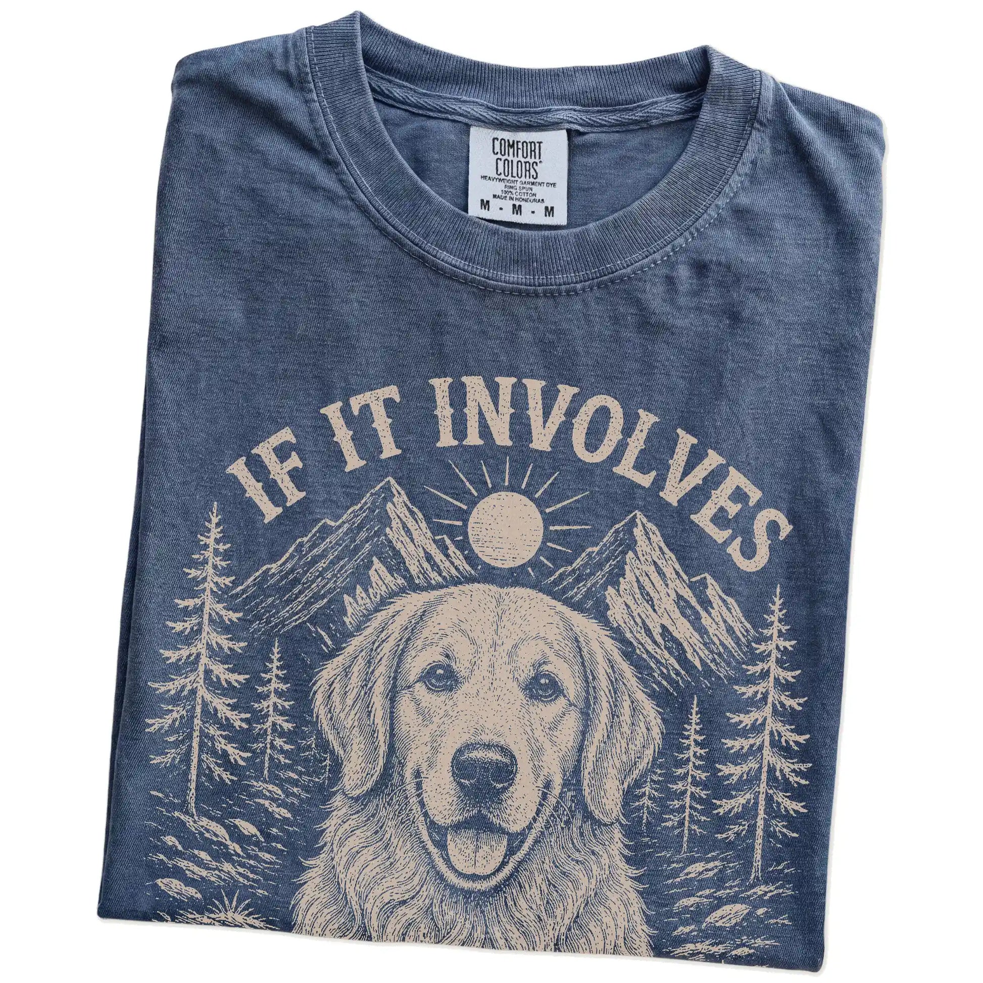 Folded Denim Comfort Colors® T-shirt showing Golden Retriever hiking design with mountain scenery