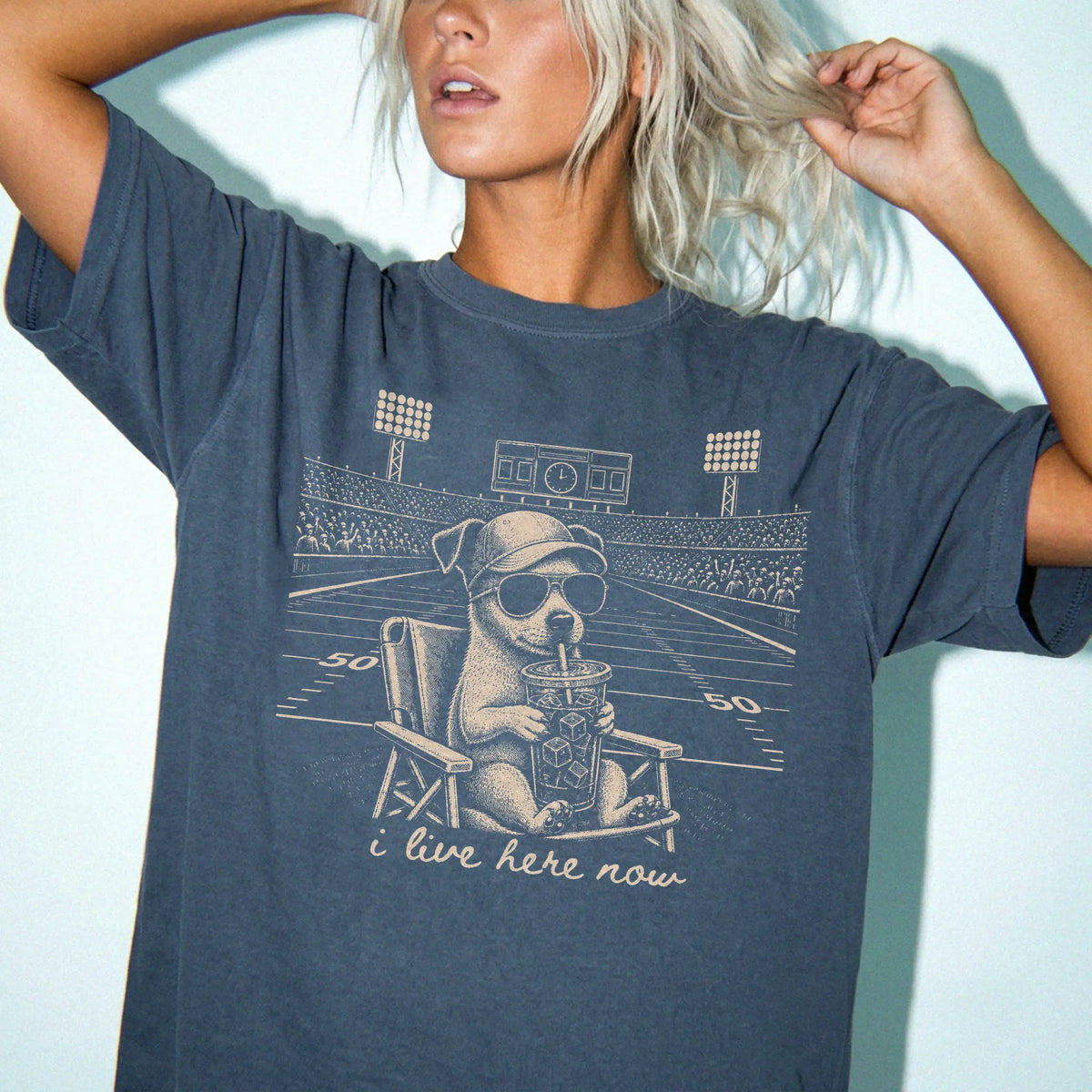 Model wearing a Denim Comfort Colors® T-shirt featuring Jack Russell claiming the football field with “I Live Here Now” lette