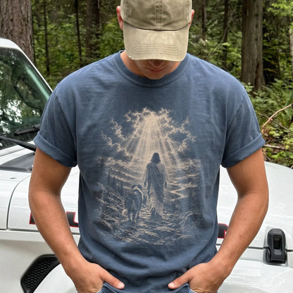 Person wearing a Denim T-shirt with Jesus walking beside a Bernese Mountain Dog beneath rays of light