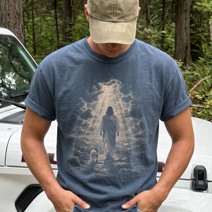 Person wearing a Denim T-shirt with Jesus walking beside a Shih Tzu beneath rays of light
