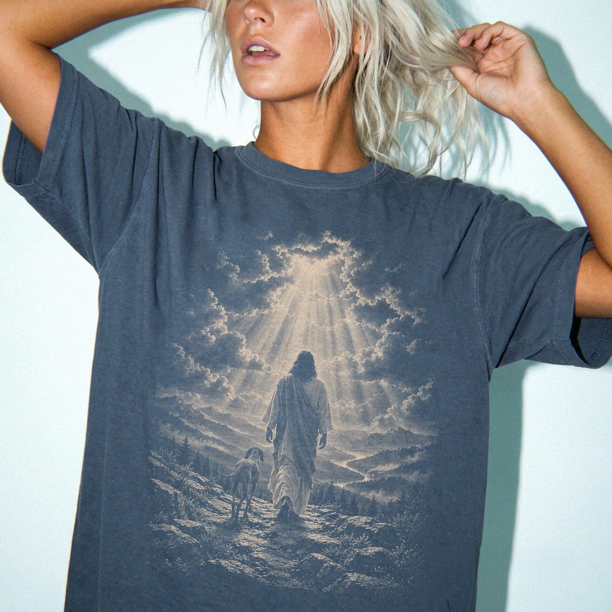 Person wearing a Denim T-shirt with Jesus walking beside a Vizsla beneath rays of light