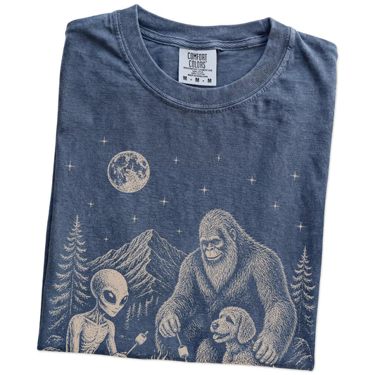 Folded Denim Comfort Colors® T-shirt showing Labradoodle camping with Bigfoot and an alien