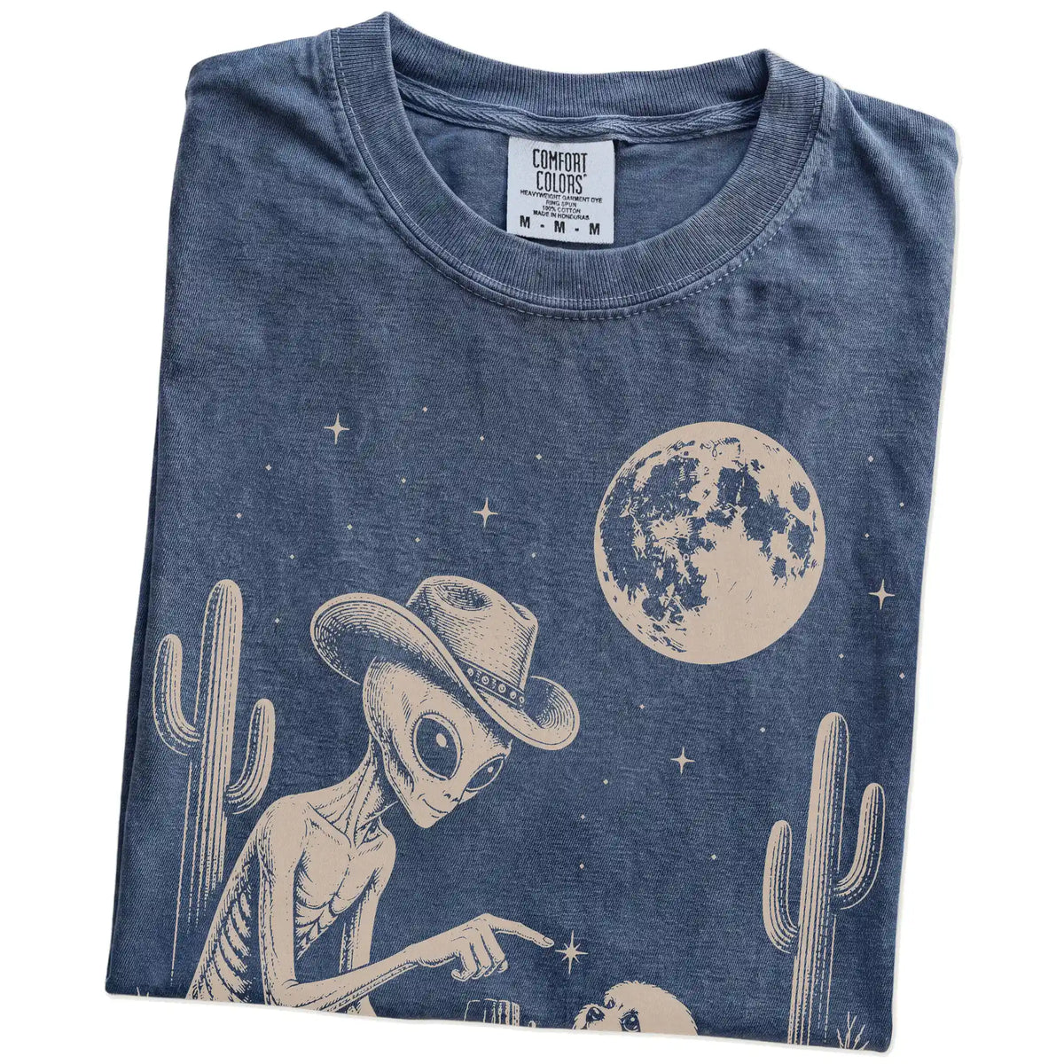 Folded Denim Comfort Colors® T-shirt showing cowboy alien fist-bumping a maltese beneath the moon