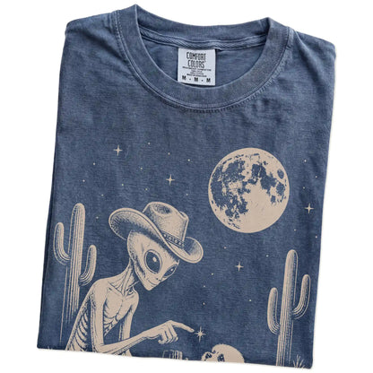 Folded Denim Comfort Colors® T-shirt showing cowboy alien fist-bumping a maltese beneath the moon
