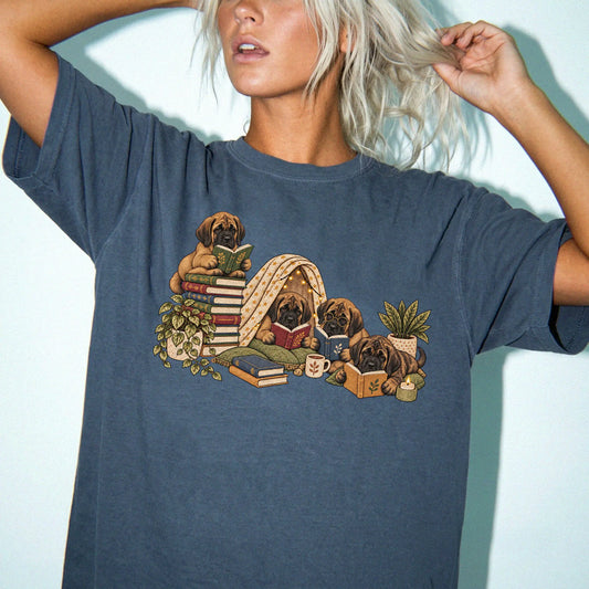Mastiff puppies reading books in a cozy blanket fort on a Denim T-shirt worn by a model