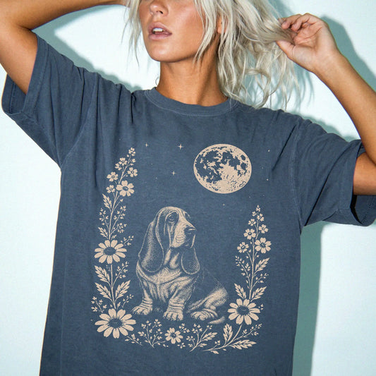 Model wearing a Denim Comfort Colors® T-shirt featuring Basset Hound framed by flowers beneath the moon
