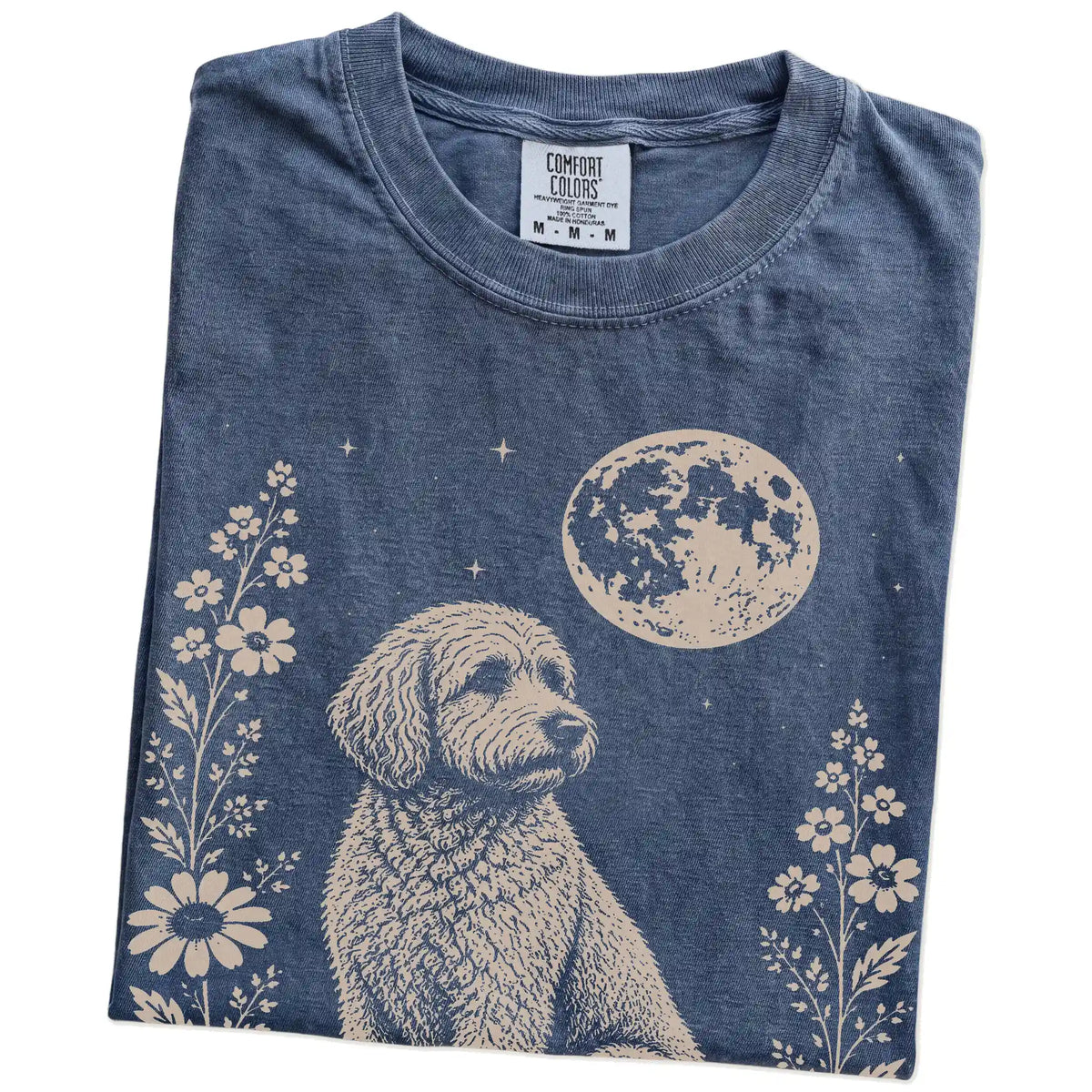 Folded Denim Comfort Colors® T-shirt showing Goldendoodle framed by flowers beneath the moon