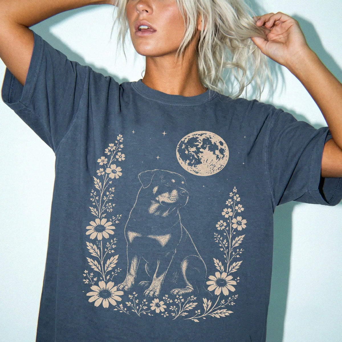 Model wearing a Denim Comfort Colors® T-shirt featuring Rottweiler framed by flowers beneath the moon